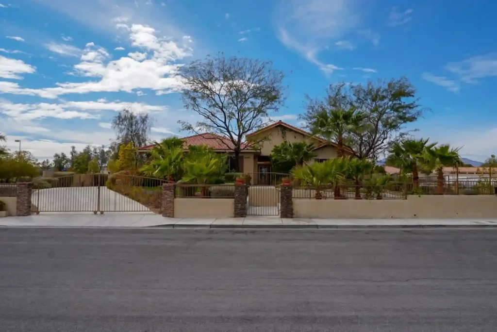 Front road view of Nevada memory care. A road, with some flowers and a boundary wall. Sky at the background.